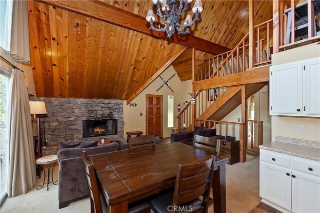 1192 Evergreen Ln, Lake Arrowhead, CA 92352 - dining area featuring wooden ceiling with exposed beams, a chandelier, light colored carpet, stairs, and a stone fireplace