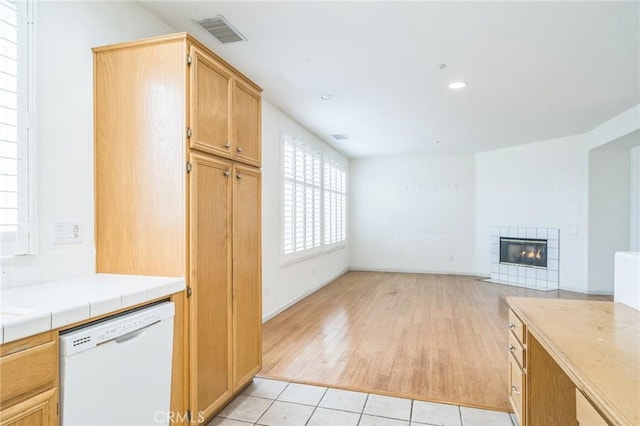 1065 Vaquero Cir, Oxnard, CA 93030 - kitchen with white dishwasher, a tile fireplace, tile counters, light wood-style floors, and recessed lighting