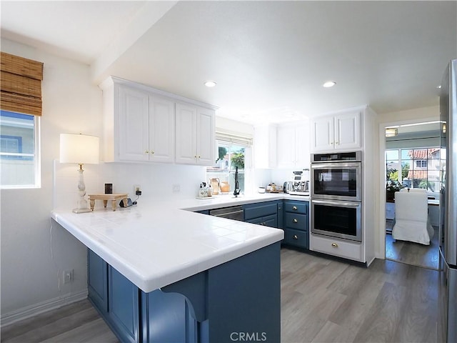 2018 Bataan Rd Unit A, Redondo Beach, CA 90278 - kitchen with stainless steel appliances, white cabinets, light wood-style floors, a peninsula, and blue cabinets