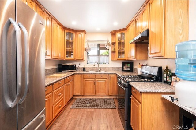 14121 Calais St, Baldwin Park, CA 91706 - kitchen featuring appliances with stainless steel finishes, under cabinet range hood, a sink, light wood-style floors, and light stone countertops