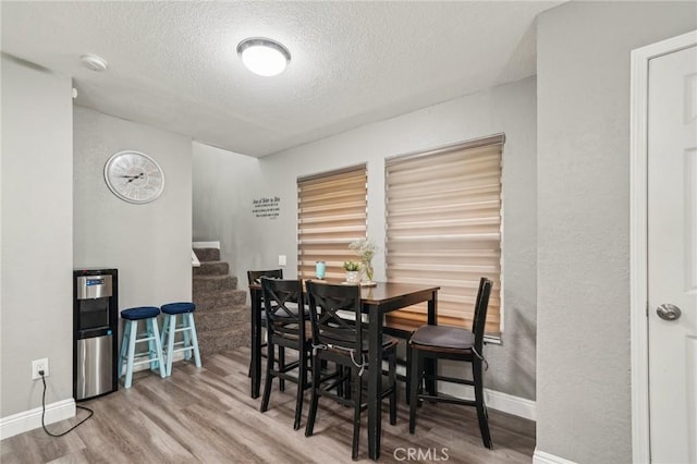 8167 Vineyard Ave Unit 109, Rancho Cucamonga, CA 91730 - dining space with wood finished floors, a textured ceiling, baseboards, and stairs