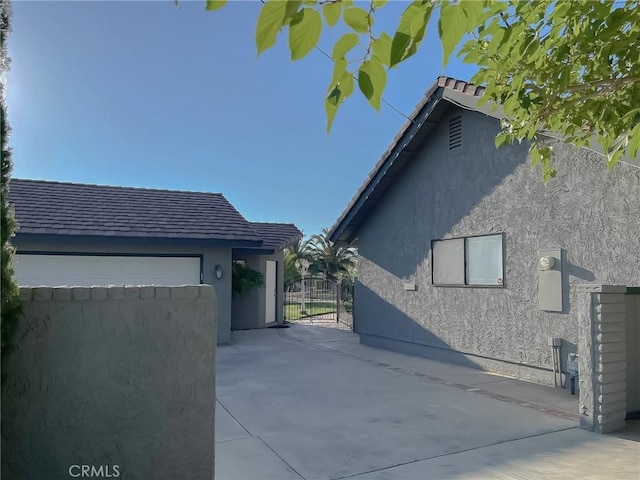42722 20th St W, Lancaster, CA 93534 - view of side of property with stucco siding, an attached garage, driveway, and a gate