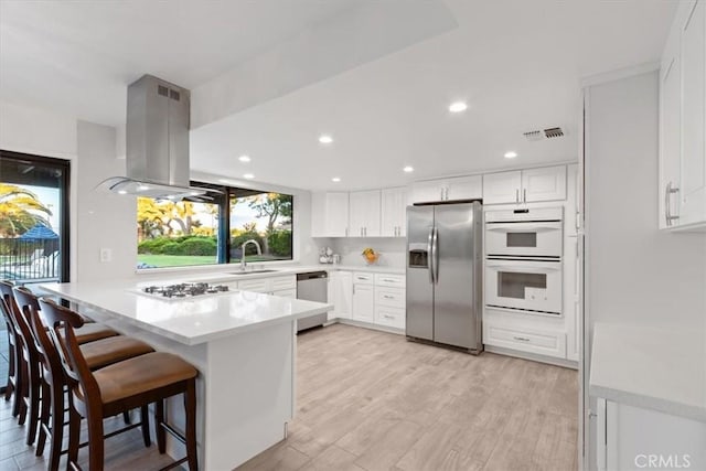 42722 20th St W, Lancaster, CA 93534 - kitchen featuring stainless steel appliances, a peninsula, island range hood, a sink, and a breakfast bar area