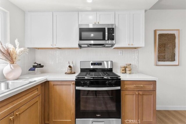 246 Aldama Ave, Pomona, CA 91767 - kitchen with stainless steel appliances, decorative backsplash, light wood-style floors, white cabinets, and light countertops