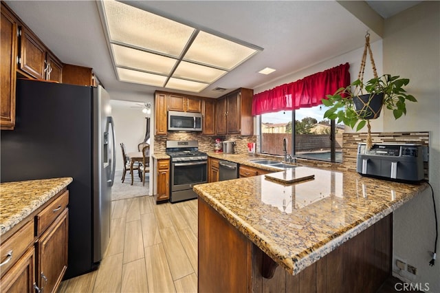 43816 Fallon Dr, Lancaster, CA 93535 - kitchen featuring stainless steel appliances, a sink, backsplash, a peninsula, and light stone countertops