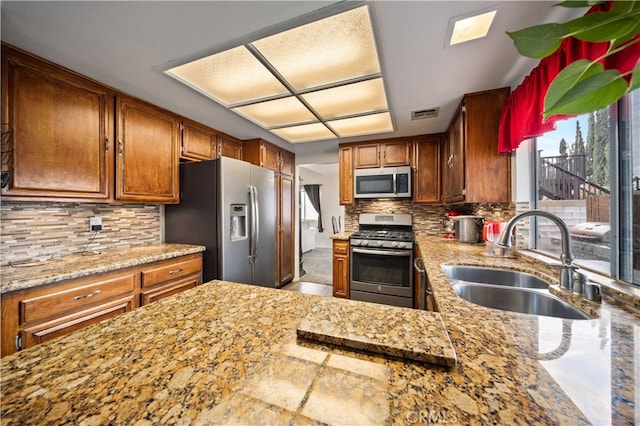 43816 Fallon Dr, Lancaster, CA 93535 - kitchen with stainless steel appliances, a sink, tasteful backsplash, and brown cabinetry