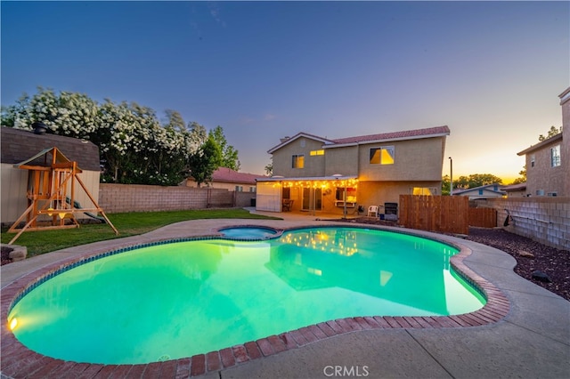 43816 Fallon Dr, Lancaster, CA 93535 - pool at dusk featuring a fenced backyard, a patio, a pool with connected hot tub, and a playground