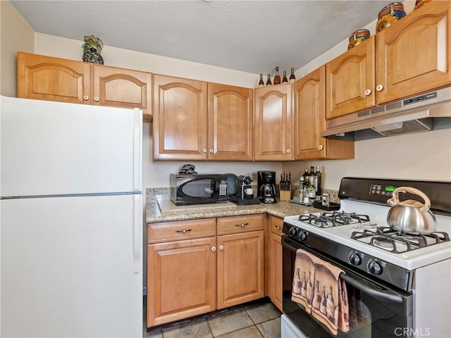 49333 Riverside Rd, Newberry Springs, CA 92365 - kitchen featuring freestanding refrigerator, range with gas stovetop, under cabinet range hood, black microwave, and light stone counters