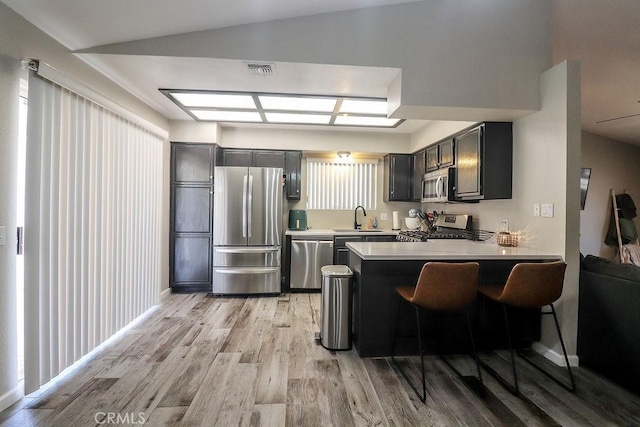 1330 Santa Fe Cir, Needles, CA 92363 - kitchen with appliances with stainless steel finishes, a sink, light wood-type flooring, a peninsula, and light countertops