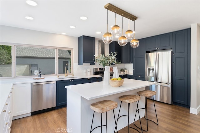 13 Aspen Tree Ln, Irvine, CA 92612 - kitchen with stainless steel appliances, a sink, a breakfast bar area, light wood-style floors, and light countertops