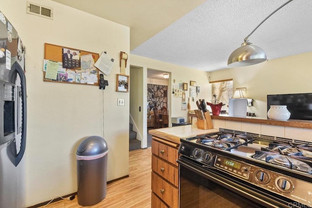 150 Richeth Rd, San Diego, CA 92114 - kitchen with gas stove, light wood-style floors, a textured ceiling, light countertops, and brown cabinets