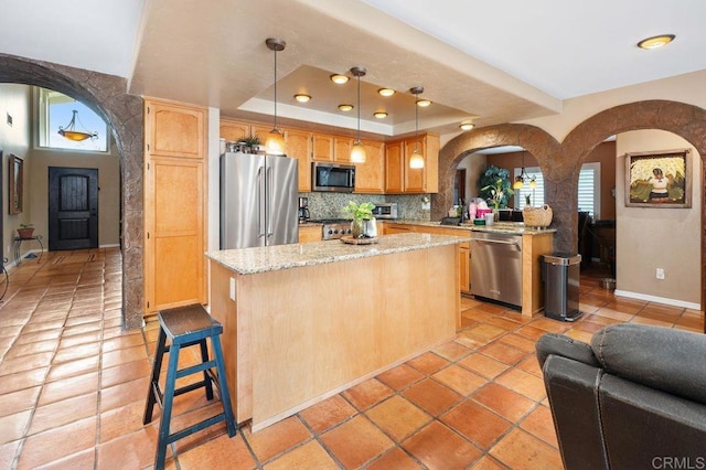 1663 Linda Sue Ln, Encinitas, CA 92024 - kitchen featuring stainless steel appliances, arched walkways, a raised ceiling, a center island, and light stone counters