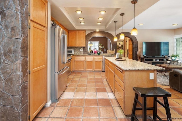 1663 Linda Sue Ln, Encinitas, CA 92024 - kitchen featuring arched walkways, appliances with stainless steel finishes, open floor plan, light brown cabinetry, and light stone counters