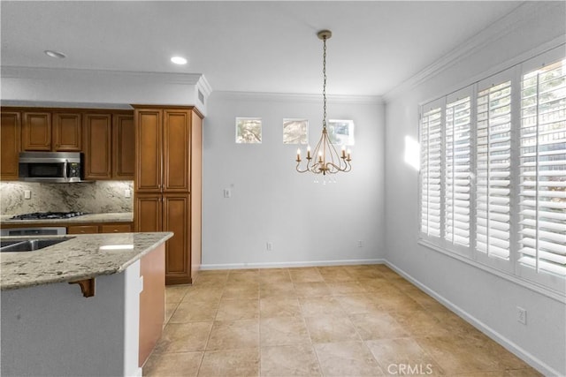 23795 Los Pinos Ct, Corona, CA 92883 - kitchen featuring stainless steel microwave, a chandelier, brown cabinetry, plenty of natural light, and crown molding