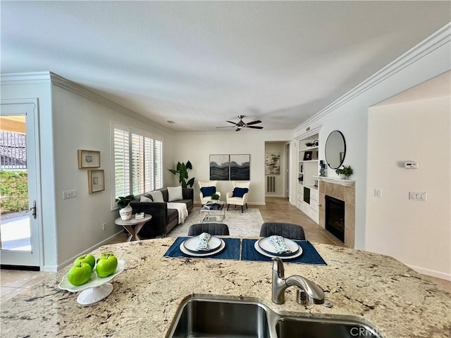 23795 Los Pinos Ct, Corona, CA 92883 - kitchen featuring a sink, ceiling fan, built in features, a tiled fireplace, and light stone countertops