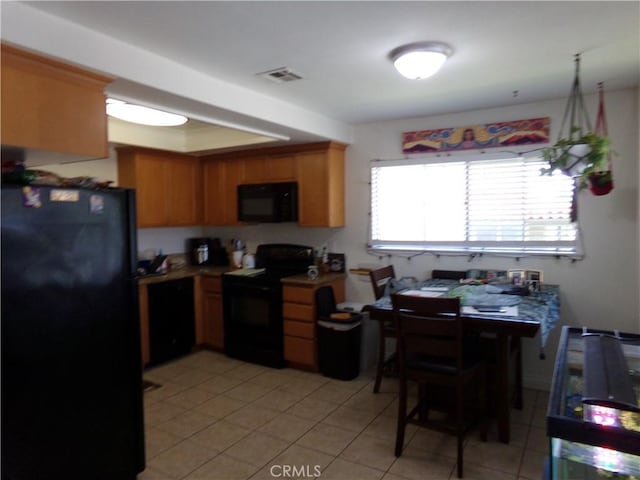 1598 Border Ave Unit H, Corona, CA 92882 - kitchen featuring black appliances, light tile patterned floors, brown cabinetry, and a raised ceiling