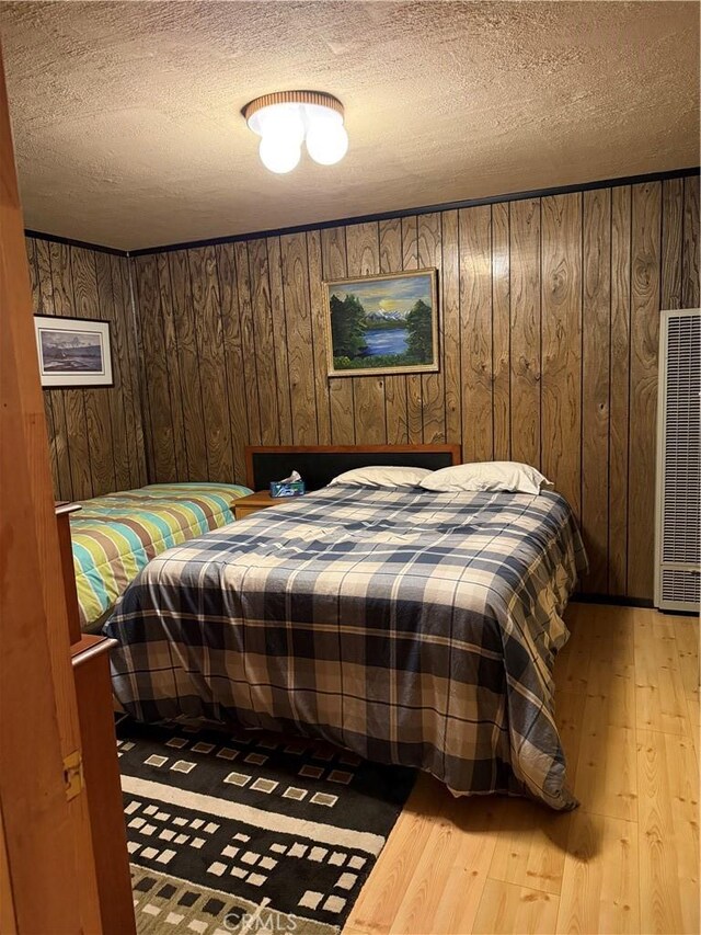 98011 Maine Rd, Kennedy Meadows, CA 93527 - bedroom with a heating unit, light wood-style flooring, a textured ceiling, and wooden walls
