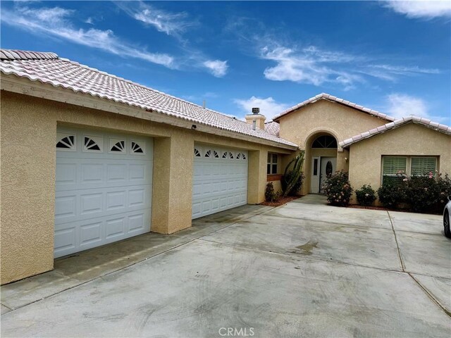 8520 Bolero Dr, Yucca Valley, CA 92284 - view of front of house with stucco siding, driveway, a garage, and a chimney