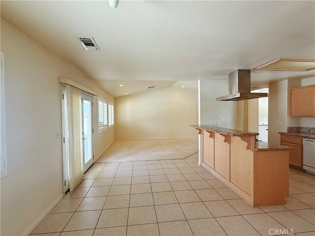 8520 Bolero Dr, Yucca Valley, CA 92284 - kitchen with wall chimney range hood, dishwasher, light tile patterned floors, a kitchen bar, and recessed lighting