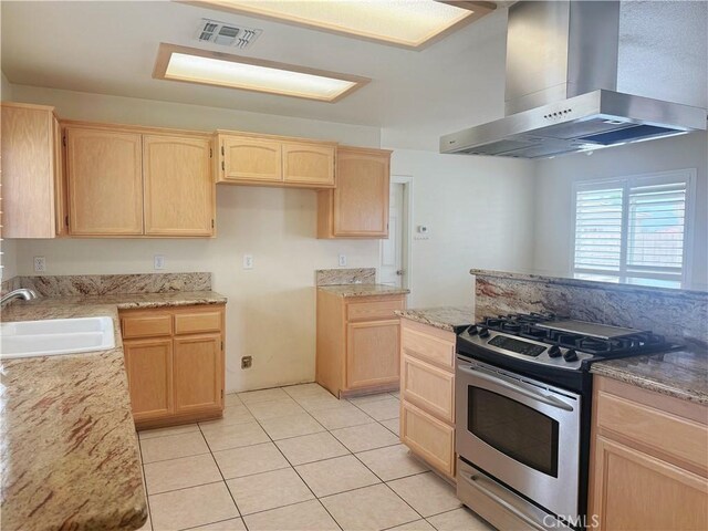 8520 Bolero Dr, Yucca Valley, CA 92284 - kitchen with wall chimney range hood, light brown cabinets, stainless steel range with gas stovetop, a sink, and light tile patterned floors