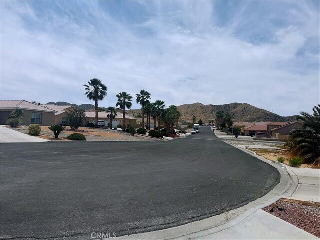 8520 Bolero Dr, Yucca Valley, CA 92284 - view of asphalt street with a residential view, a mountain view, and curbs