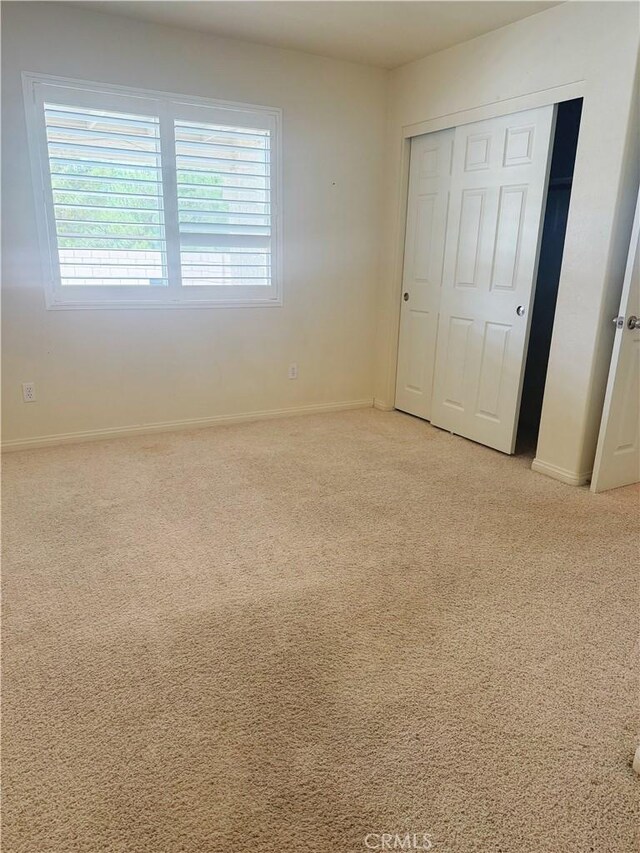 8520 Bolero Dr, Yucca Valley, CA 92284 - unfurnished bedroom with light colored carpet, baseboards, and a closet