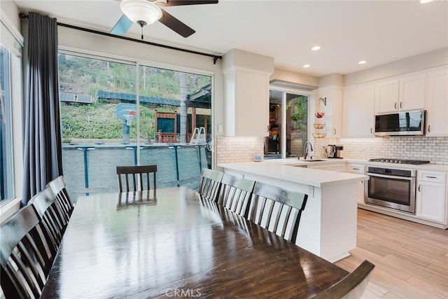 20019 Franks Way, Saugus, CA 91350 - kitchen featuring appliances with stainless steel finishes, a sink, backsplash, white cabinetry, and light wood-style floors