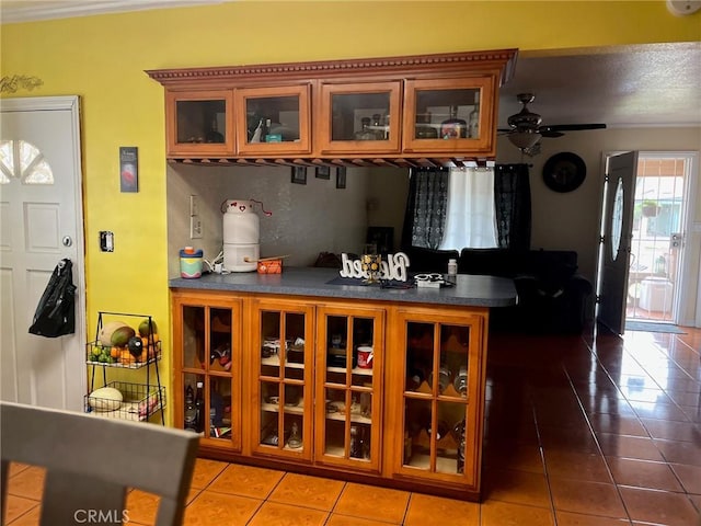 2730 Walnut St, Huntington Park, CA 90255 - kitchen featuring tile patterned flooring, dark countertops, a ceiling fan, brown cabinets, and glass insert cabinets