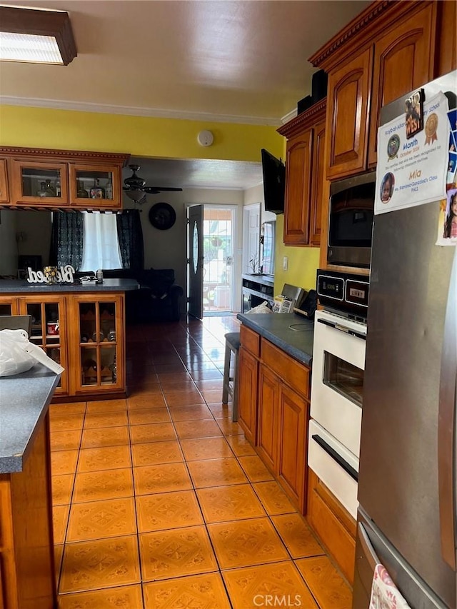 2730 Walnut St, Huntington Park, CA 90255 - kitchen with appliances with stainless steel finishes, a warming drawer, brown cabinets, light tile patterned flooring, and dark countertops
