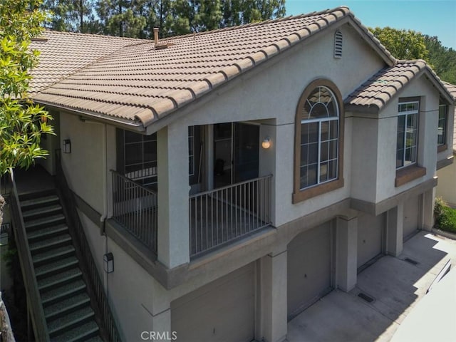369 Chaumont Cir, Lake Forest, CA 92610 - view of side of home with stucco siding, a tile roof, an attached garage, and stairway