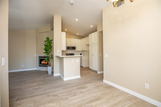 369 Chaumont Cir, Lake Forest, CA 92610 - kitchen with stainless steel microwave, light countertops, open floor plan, lofted ceiling, and light wood-style floors