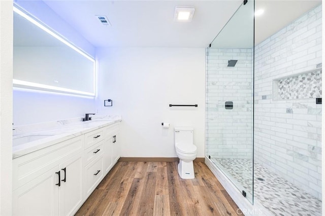 1563 Gary Ln, Redlands, CA 92374 - bathroom featuring wood finished floors, tiled shower, toilet, double vanity, and baseboards