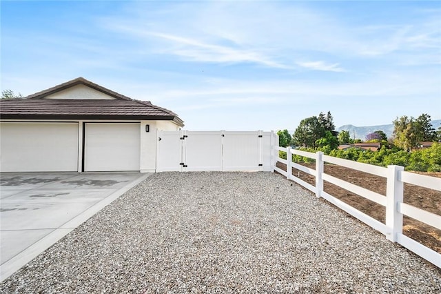 1563 Gary Ln, Redlands, CA 92374 - view of side of property with a gate, concrete driveway, a mountain view, and a tile roof
