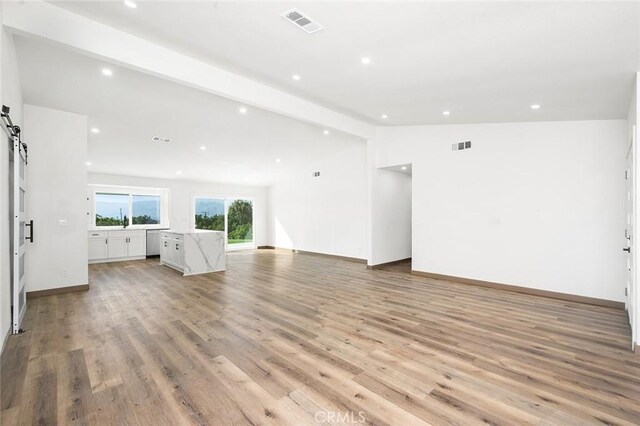 1563 Gary Ln, Redlands, CA 92374 - unfurnished living room with light wood finished floors, recessed lighting, a barn door, a sink, and baseboards