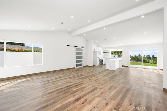 1563 Gary Ln, Redlands, CA 92374 - unfurnished living room with a barn door, healthy amount of natural light, light wood-style floors, recessed lighting, and a sink