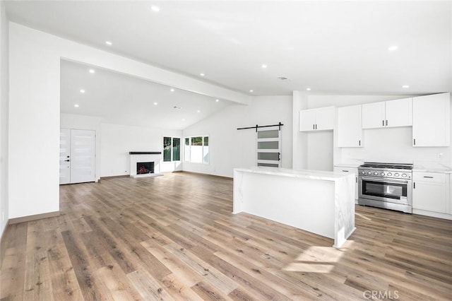 1563 Gary Ln, Redlands, CA 92374 - kitchen with high end stainless steel range, a barn door, white cabinetry, light wood-style flooring, and recessed lighting