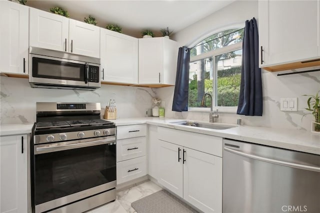 30902 Clubhouse Dr Unit 27D, Laguna Niguel, CA 92677 - kitchen featuring appliances with stainless steel finishes, light marble finish floors, a sink, white cabinetry, and decorative backsplash