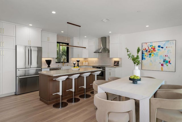 164 Cherry Ave, Carlsbad, CA 92008 - kitchen featuring stainless steel appliances, wall chimney exhaust hood, backsplash, a center island, and a breakfast bar area