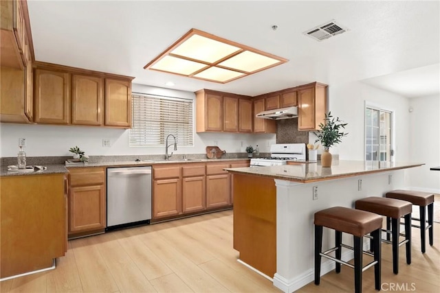 609 E Newmark Ave, Monterey Park, CA 91755 - kitchen with stainless steel dishwasher, under cabinet range hood, white range with gas cooktop, a breakfast bar area, and light wood-type flooring