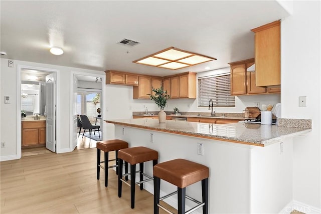 609 E Newmark Ave, Monterey Park, CA 91755 - kitchen featuring a peninsula, a breakfast bar area, light wood-style flooring, and light stone counters
