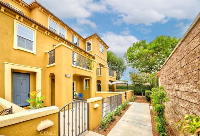 10410 Orchid Way, Santa Fe Springs, CA 90670 - view of property exterior with a balcony, a fenced front yard, a gate, and stucco siding
