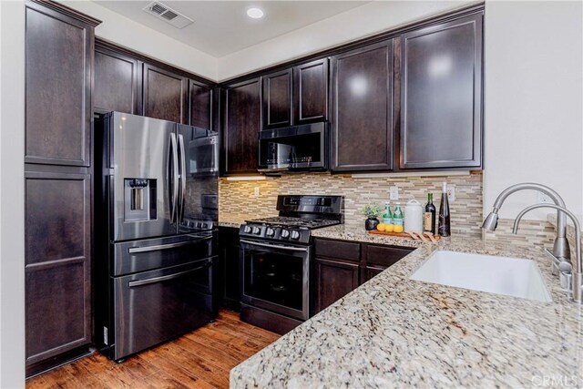 10410 Orchid Way, Santa Fe Springs, CA 90670 - kitchen with stainless steel fridge, black microwave, range with gas stovetop, light stone counters, and light wood finished floors