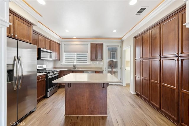 11506 Cuervo Way, Atascadero, CA 93422 - kitchen with stainless steel appliances, crown molding, a sink, light wood finished floors, and a kitchen island