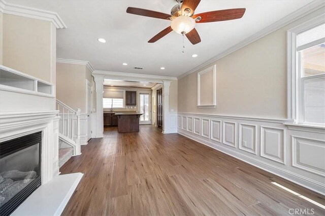 11506 Cuervo Way, Atascadero, CA 93422 - unfurnished living room featuring ornamental molding, decorative columns, a decorative wall, wood finished floors, and a ceiling fan