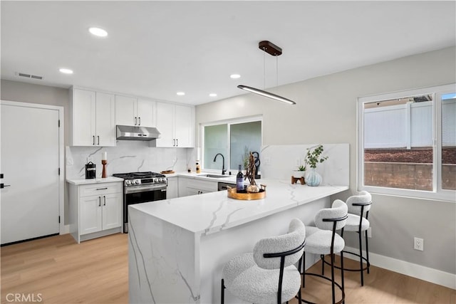 2014 Cumberland Rd, Glendora, CA 91741 - kitchen featuring stainless steel gas stove, under cabinet range hood, a peninsula, a sink, and white cabinetry