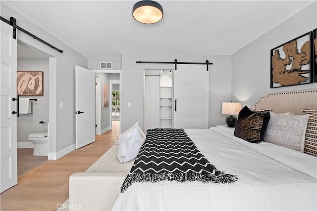 2014 Cumberland Rd, Glendora, CA 91741 - bedroom with a barn door, light wood-style floors, ensuite bathroom, and baseboards