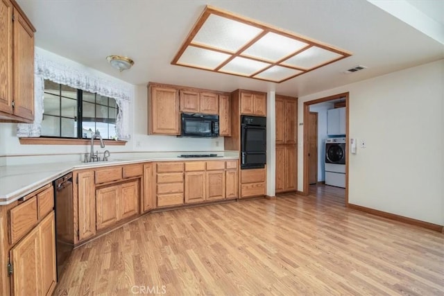 312 Crystal Cir, Lompoc, CA 93436 - kitchen with washer / dryer, a sink, a warming drawer, black appliances, and light wood-style flooring