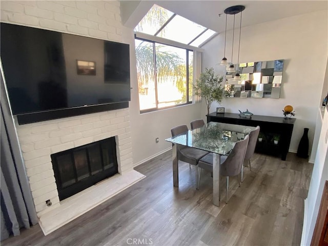 17722 Sergio Cir Unit 203, Huntington Beach, CA 92647 - dining room with wood finished floors, a fireplace, baseboards, and vaulted ceiling