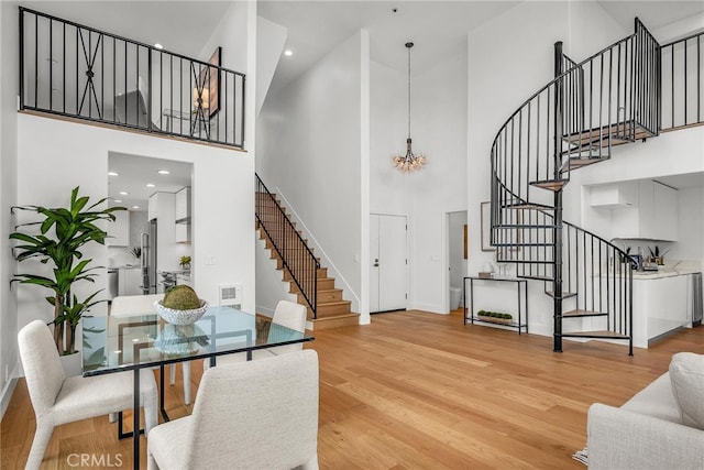 200 S Catalina Ave Unit 403, Redondo Beach, CA 90277 - dining space featuring stairway, a high ceiling, light wood-style flooring, a chandelier, and baseboards