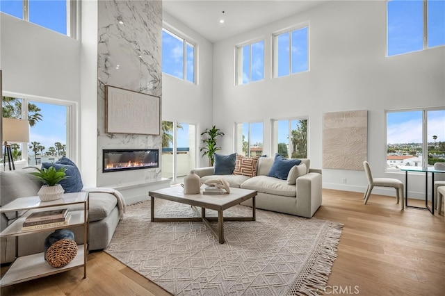 200 S Catalina Ave Unit 403, Redondo Beach, CA 90277 - living room featuring a towering ceiling, light wood-style floors, a fireplace, baseboards, and recessed lighting